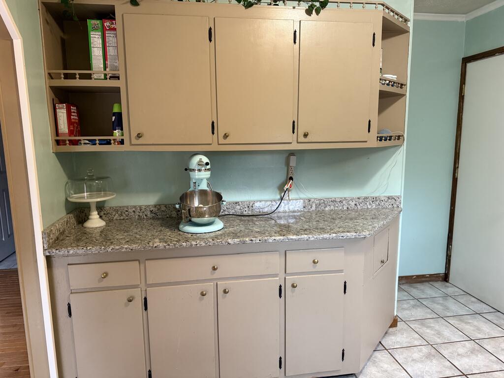 Kitchen work area with cream cabinets, open shelves, and a stand mixer on the countertop.