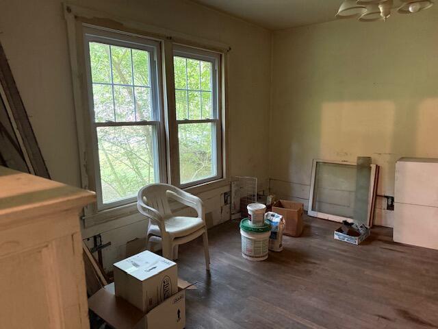Unfurnished room with two tall windows, a ceiling fan, and boxes and paint buckets on the floor.