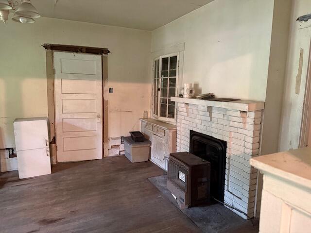 Empty room with a white brick fireplace, freestanding wood stove, and paneled door.
