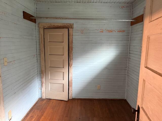 Vacant room with plank walls, worn wood flooring, and two paneled doors.