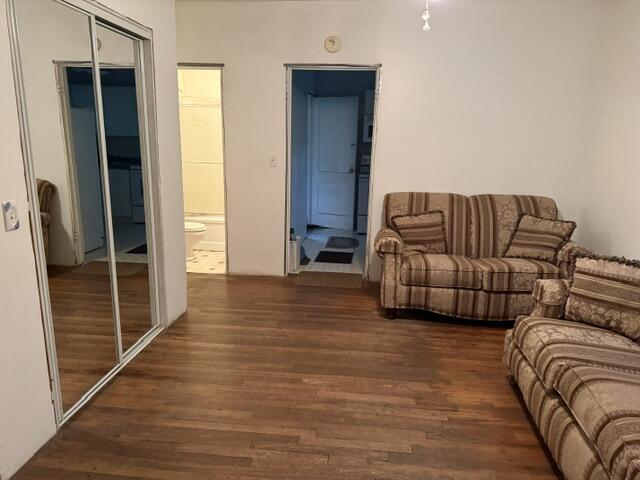 Living room with two patterned sofas, wood flooring, and mirrored closet doors.