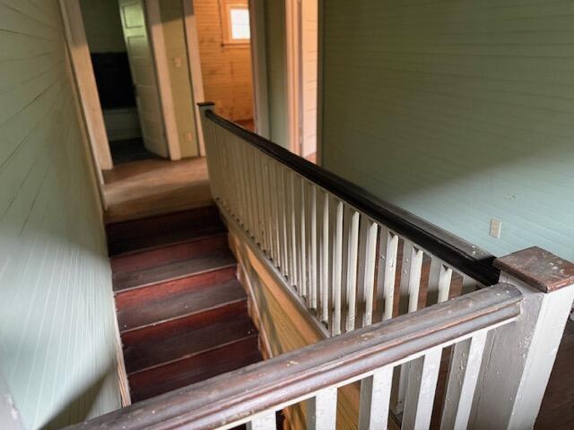 Wooden staircase with dark treads, white balusters, and pale green paneled walls.