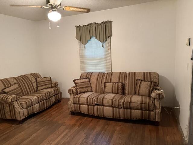 Living room with two brown striped sofas, wood floors, and a curtained window.