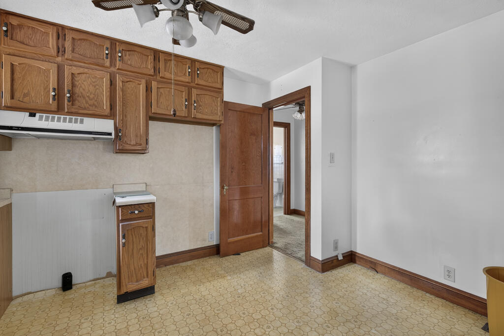 Kitchen with wood cabinets, patterned vinyl flooring, and a doorway toward a bathroom.