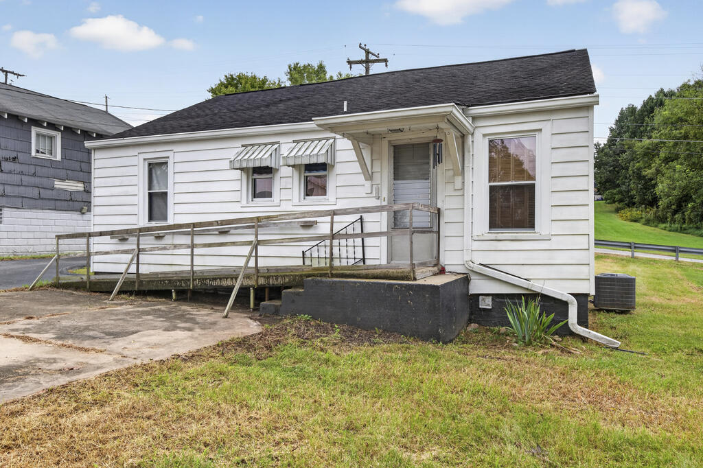 Single-story white house with a wooden accessibility ramp leading to its covered entrance.