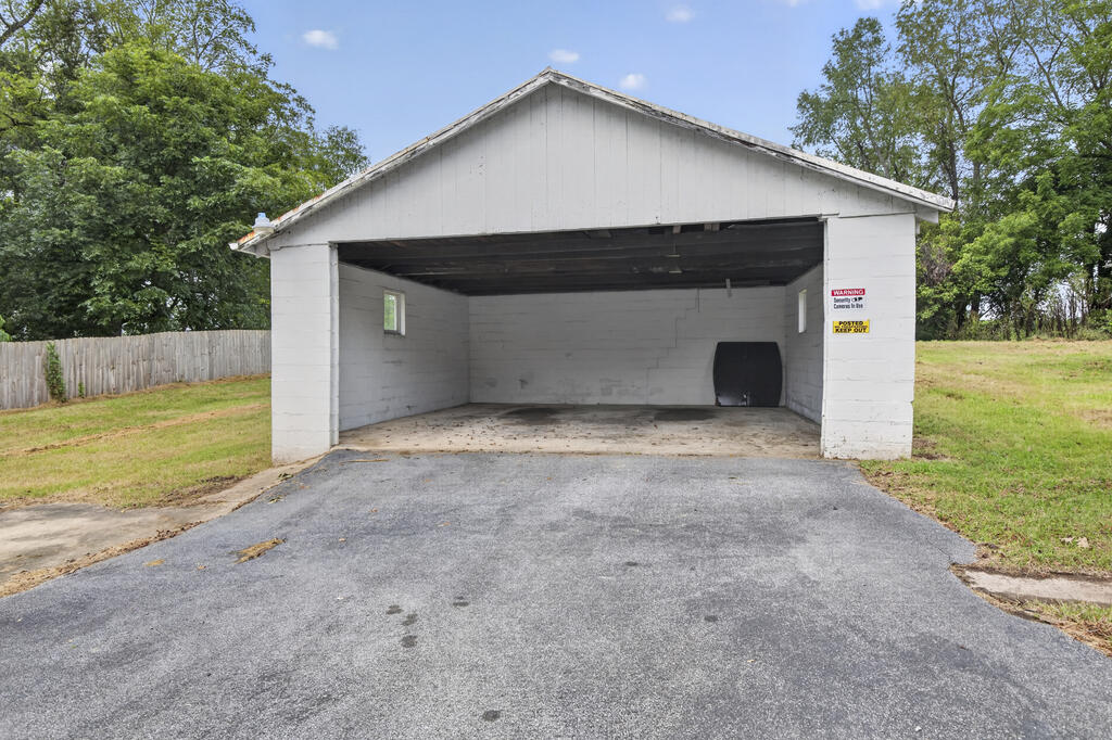 Detached white garage with an open front and a wide paved driveway.