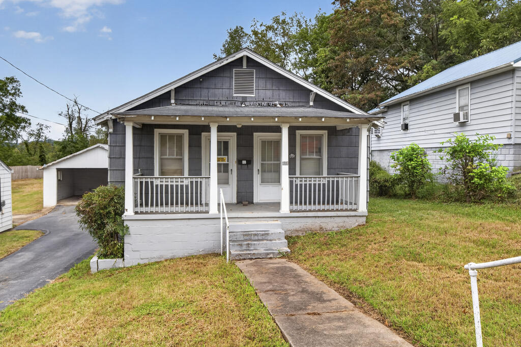 Gray single-story house with a covered front porch and driveway-side carport.