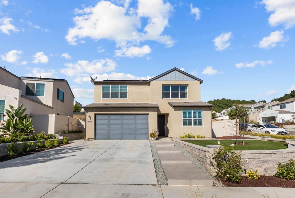 Two-story beige home with a double garage, wide driveway, and landscaped front yard.