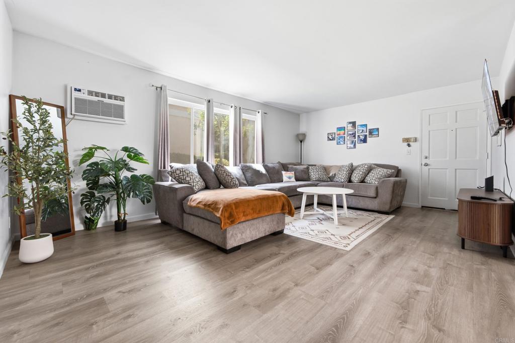Living room with a gray sectional sofa, orange throw, and large windows.