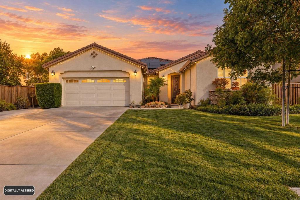 Stucco home with a double garage, broad lawn, and driveway at sunset.
