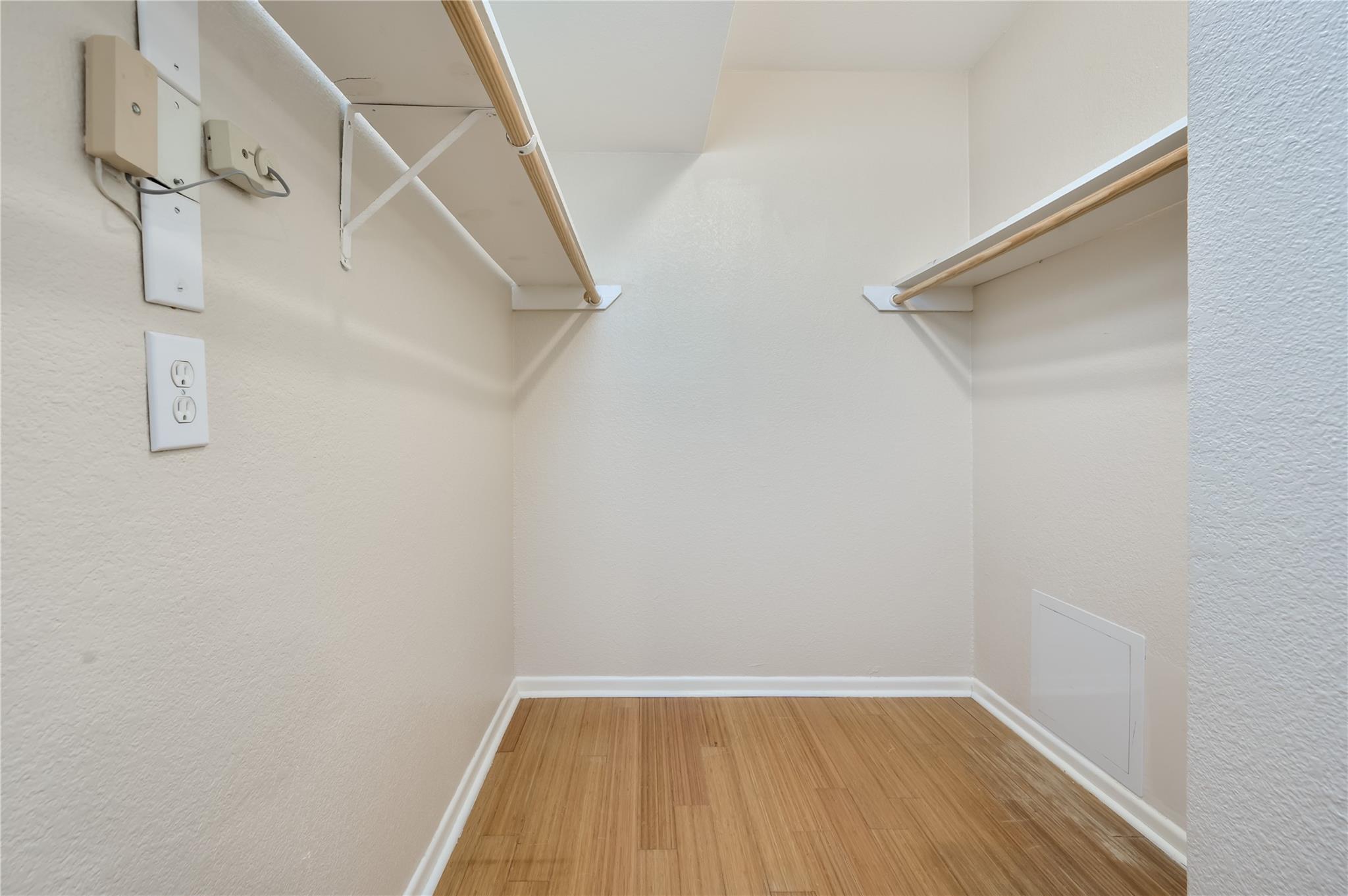 Empty closet with two wooden hanging rods and a wood-look floor