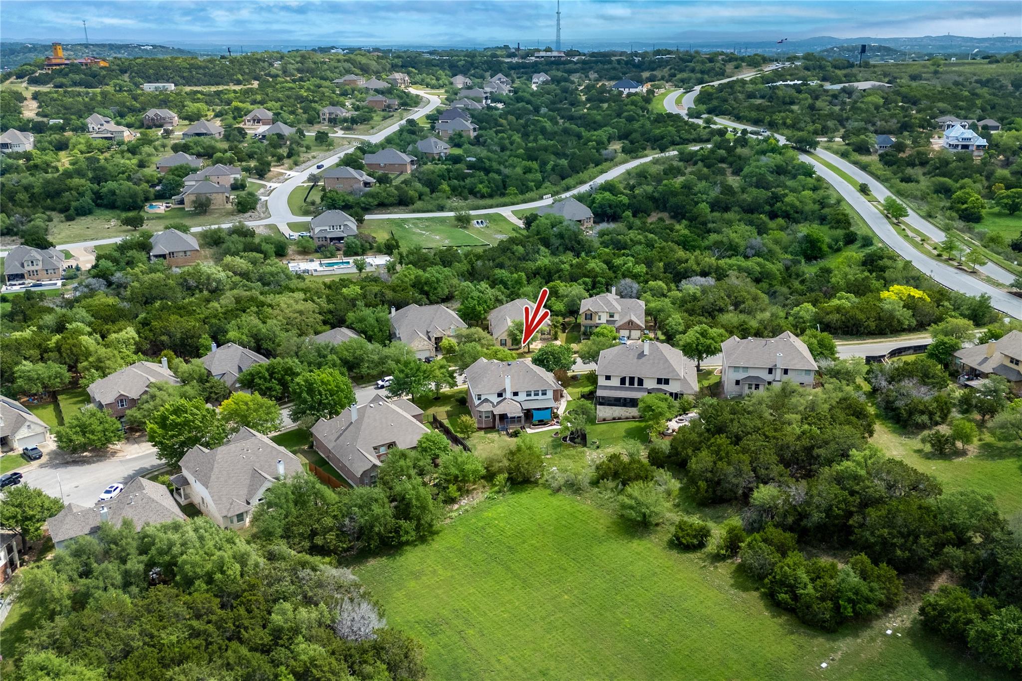 Aerial view of the home marked by a red arrow in a wooded neighborhood.