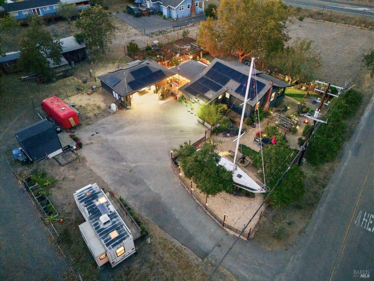 Aerial view of a home and spacious lot with solar panels, an RV, and a sailboat.