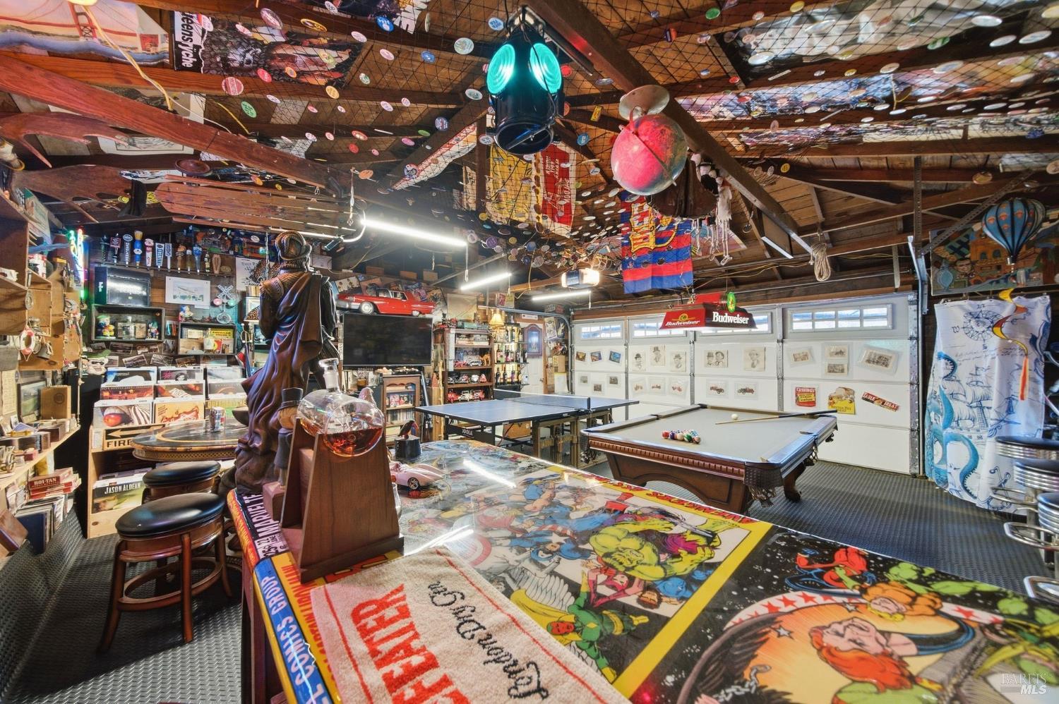 Eclectic game room with a pool table, ping-pong table, and memorabilia covering the walls and ceiling.