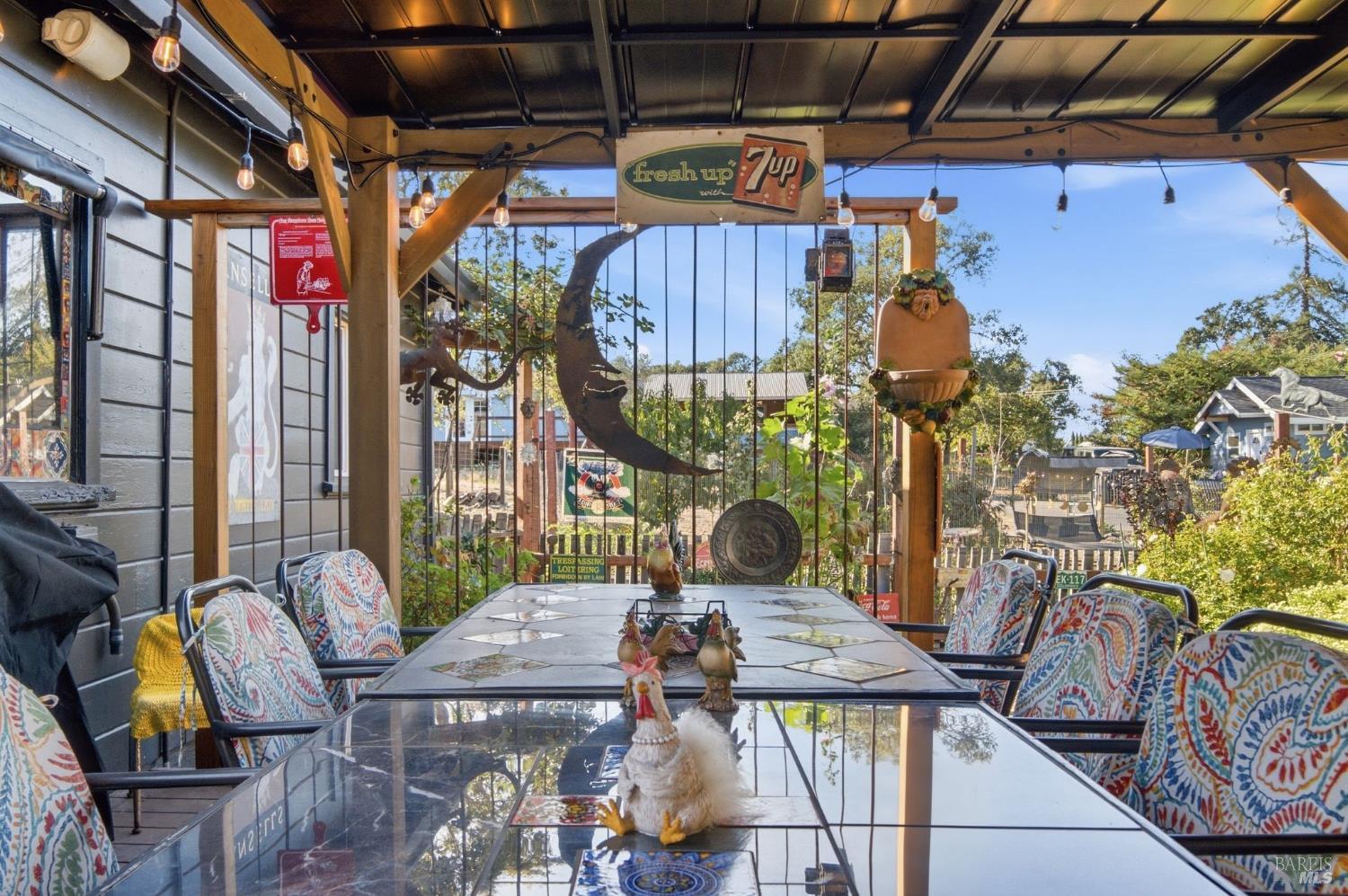 Covered patio with a glass dining table, colorful chairs, and a vintage 7up sign.