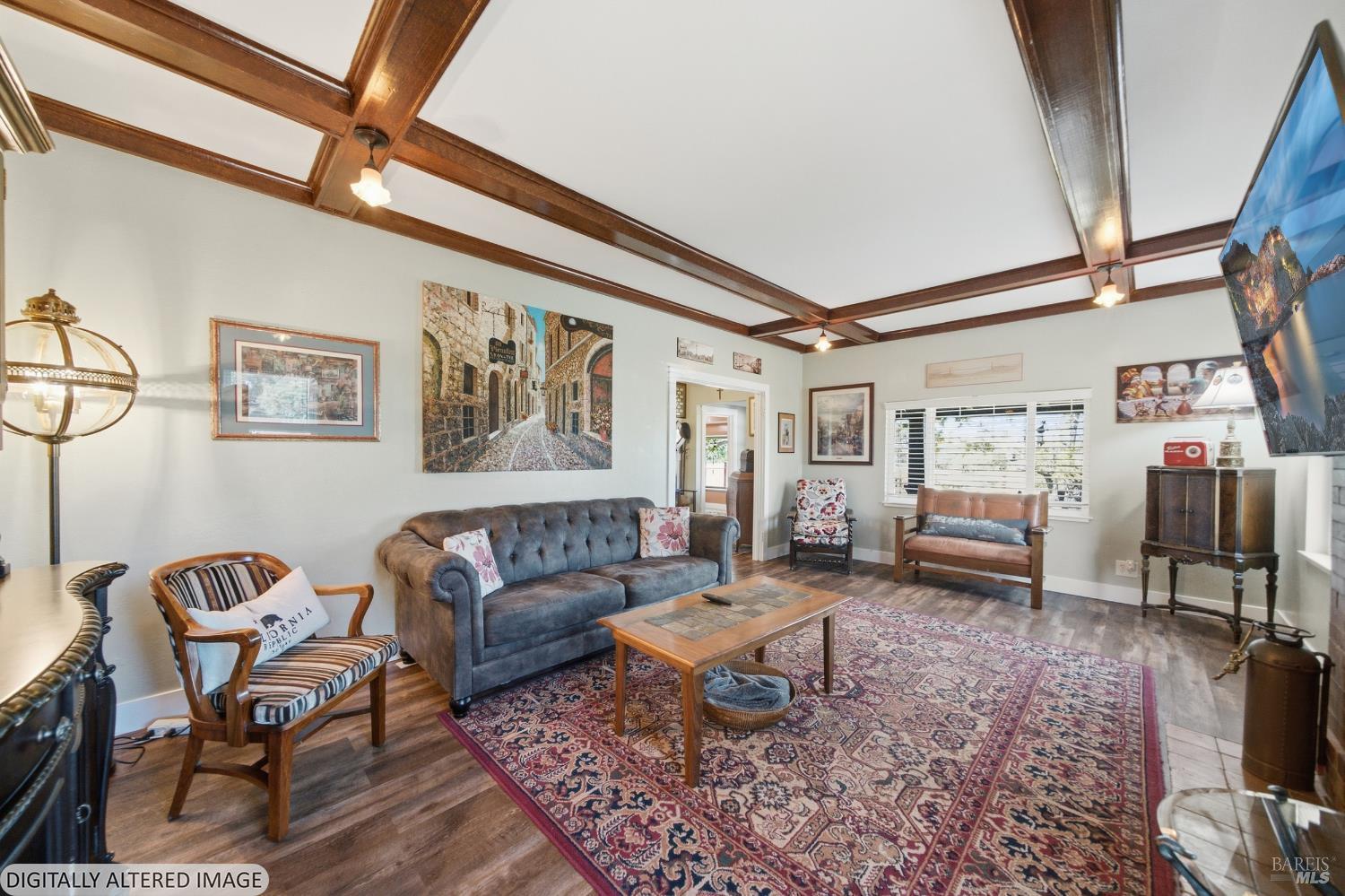 Living room with exposed wood ceiling beams, gray sofa, and large patterned rug