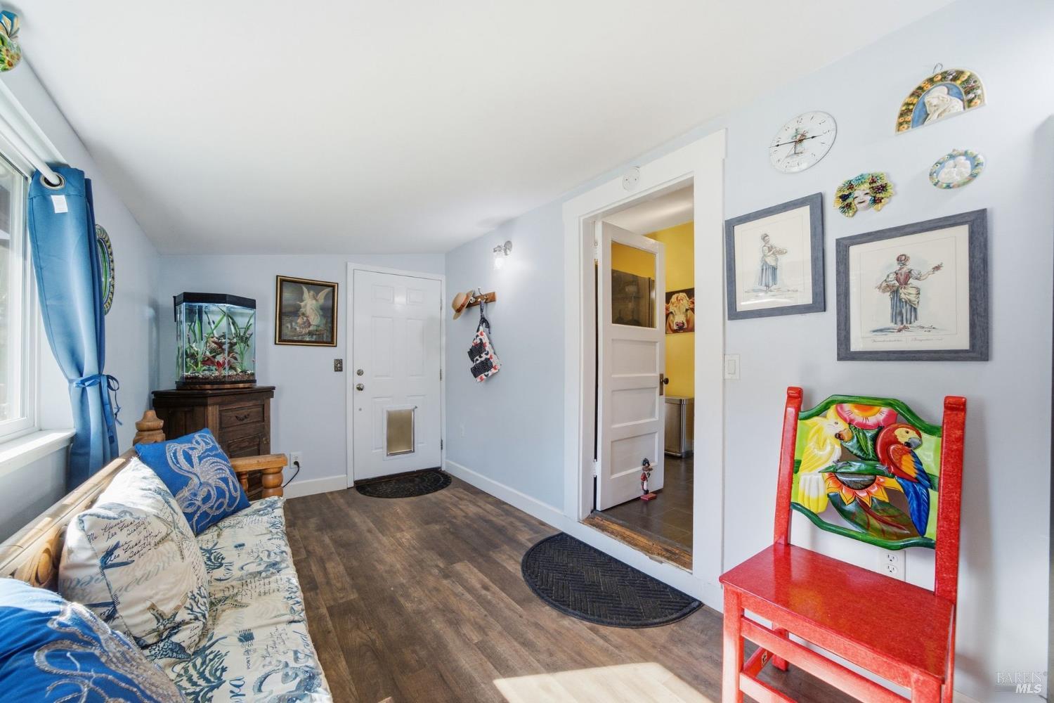 Furnished sitting room with a patterned sofa, aquarium, and bright red chair beside the entryway.