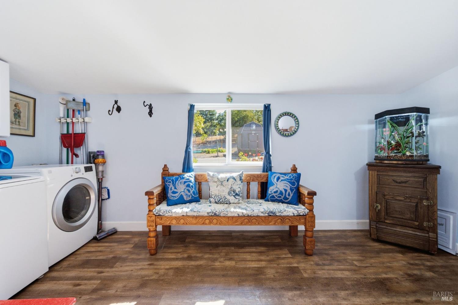 Furnished room with a washer, carved wooden loveseat, and planted aquarium.