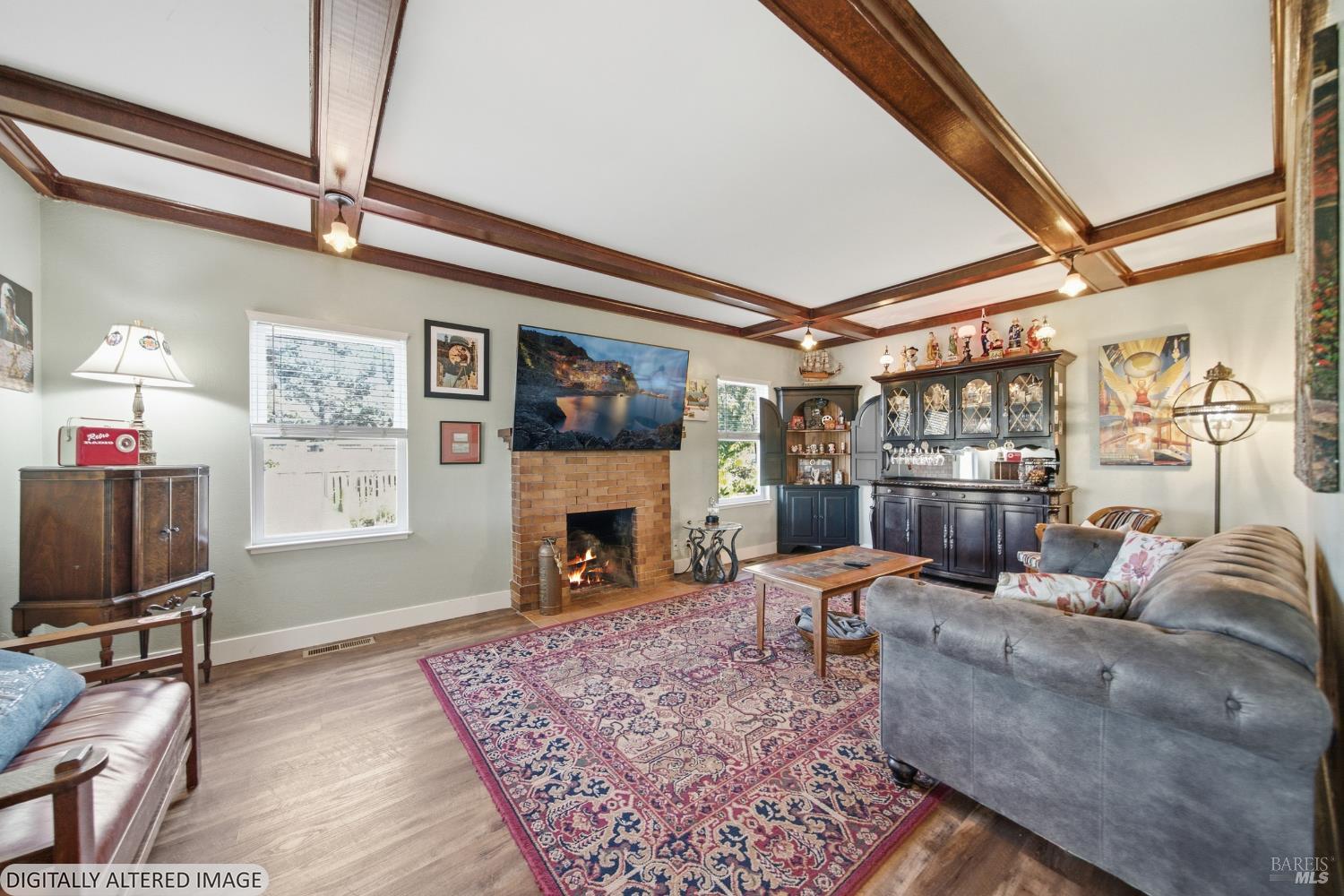 Living room with exposed ceiling beams, brick fireplace, patterned rug, and built-in bar.