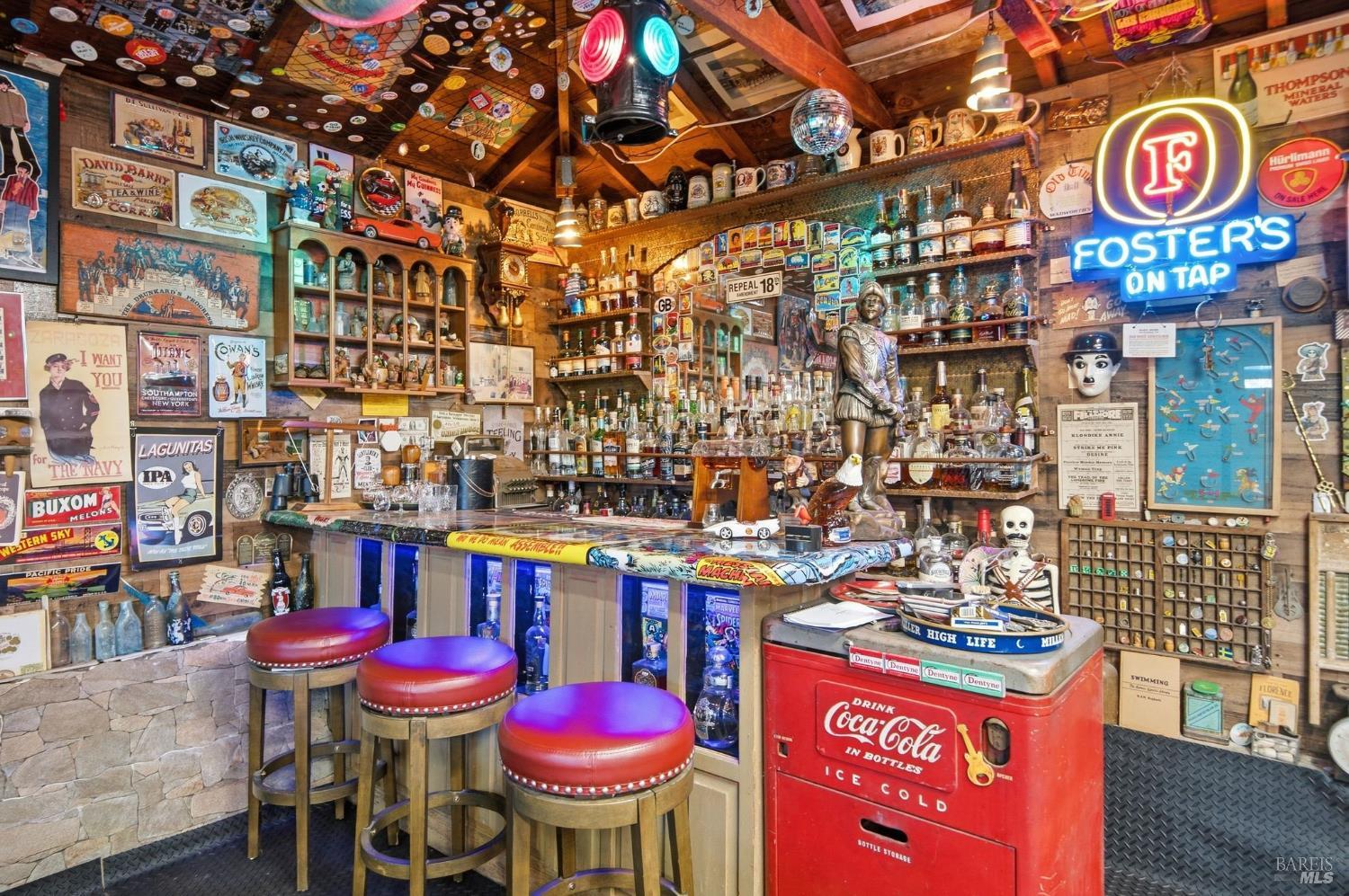 Interior bar with a neon Foster’s sign, vintage memorabilia, and a red Coca-Cola cooler.