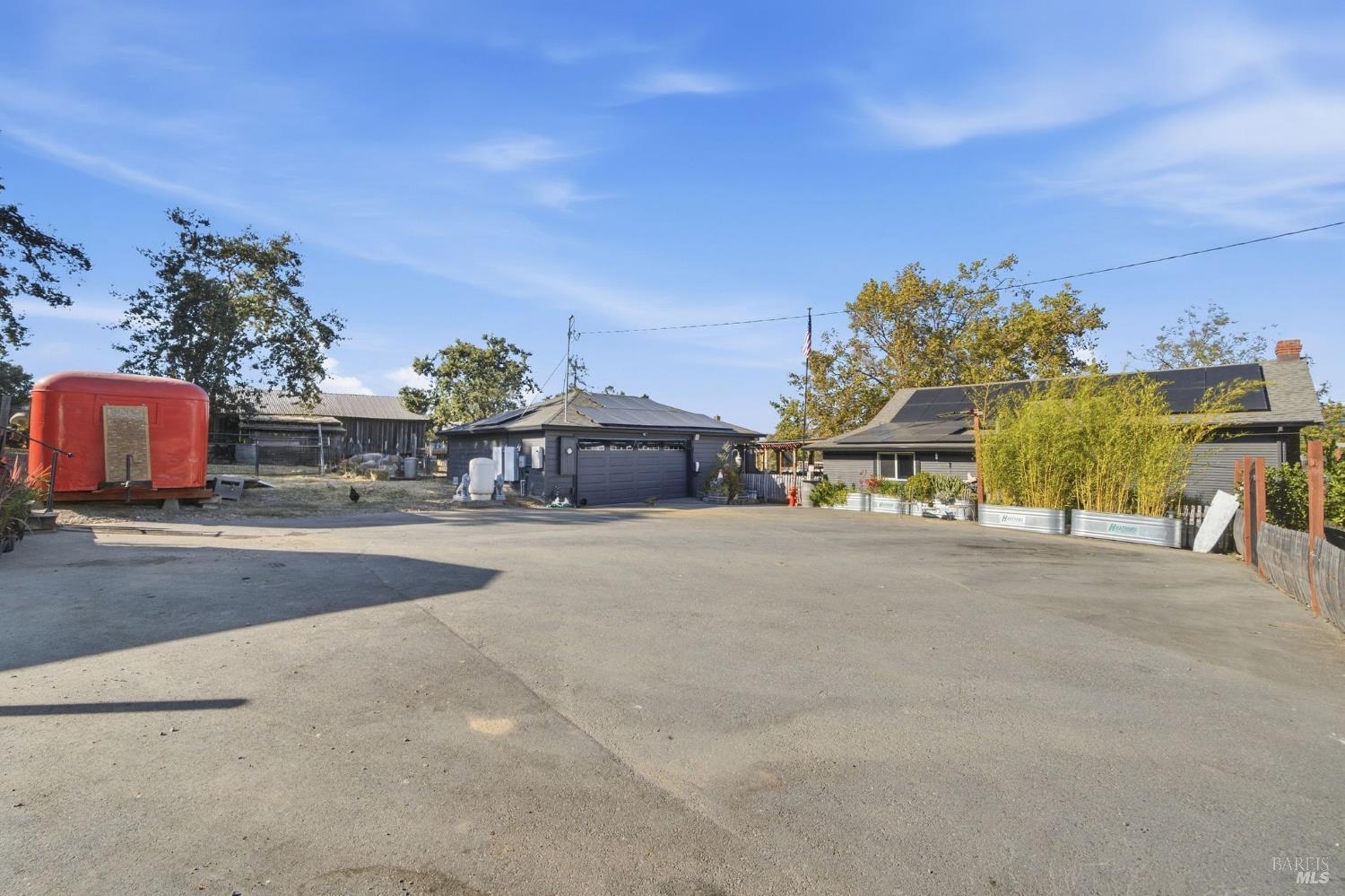 Property courtyard with solar-panelled buildings, garage, and red trailer.