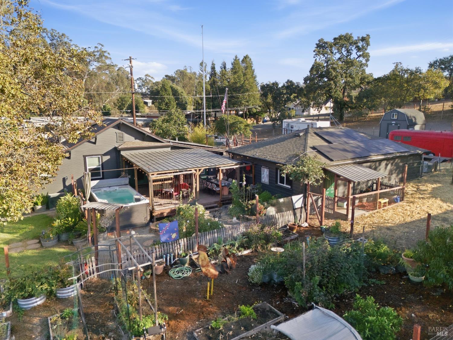 Property viewed from above, with a fenced garden, covered patio, and outdoor hot tub.