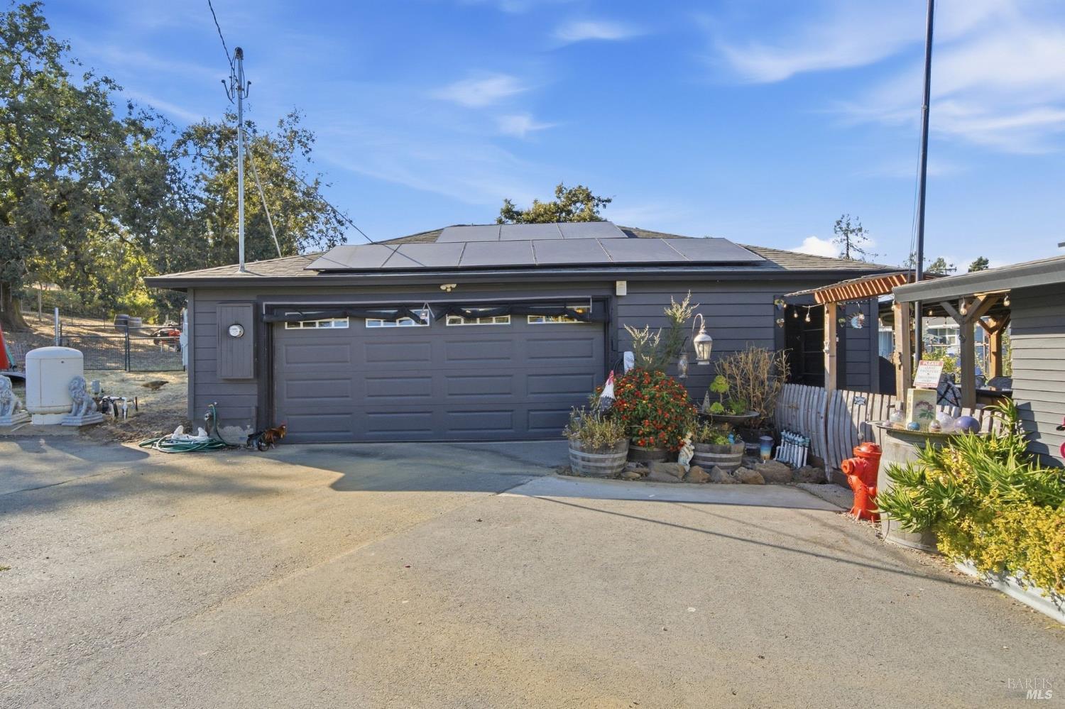 Gray home with rooftop solar panels, a wide double garage, and a covered patio.