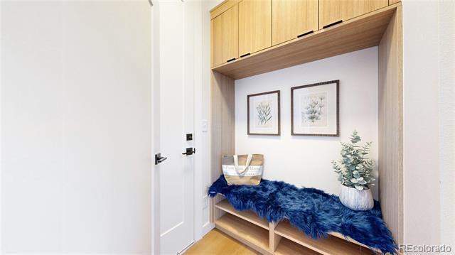 Entryway with a built-in wood bench, blue throw, framed botanical prints, and overhead cabinets.