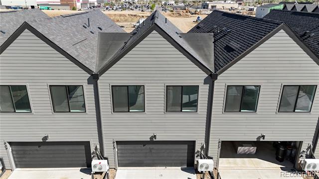 Elevated view of three attached townhomes with gabled roofs and garages, including an open garage bay.