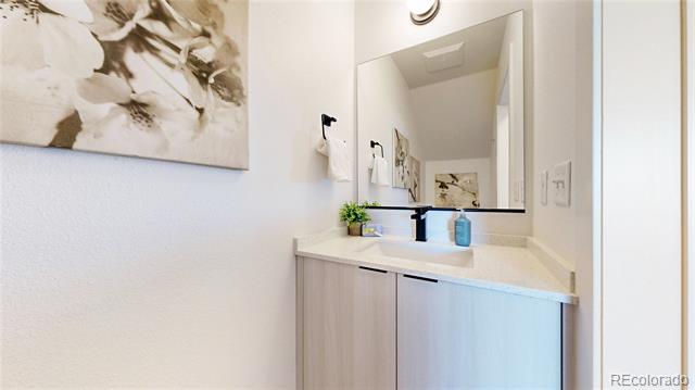 Bathroom vanity with a large mirror, black faucet, and pale wood cabinets.
