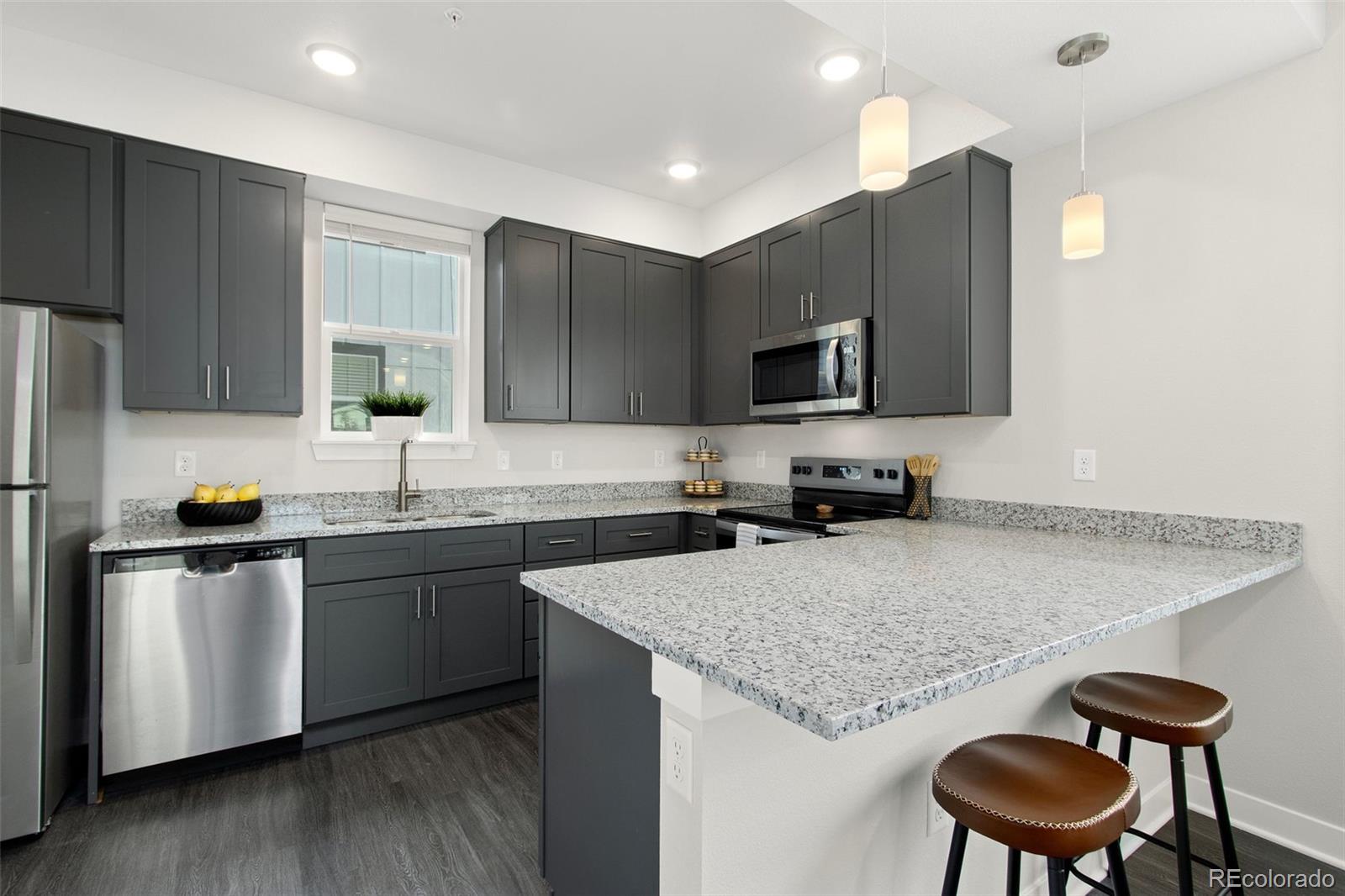 Modern kitchen with dark cabinetry, granite counters, stainless appliances, and a breakfast bar.