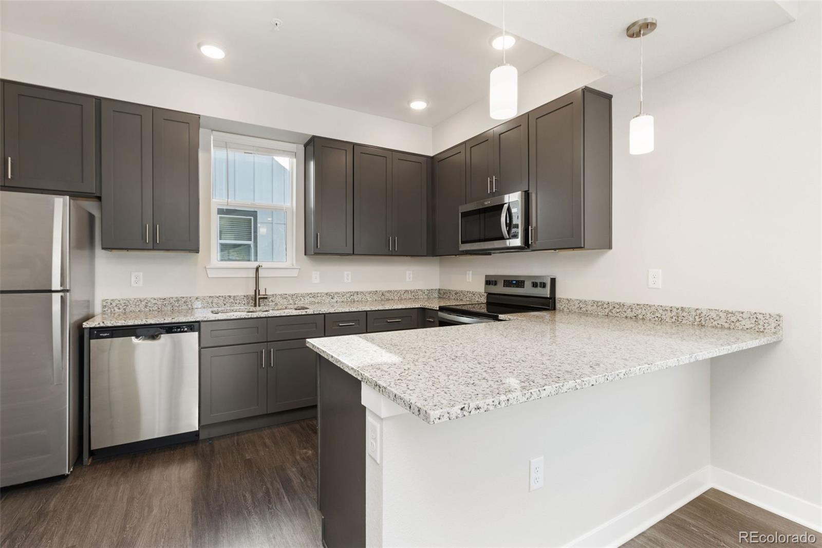 Kitchen with dark cabinets, granite counters, stainless steel appliances, and a breakfast peninsula.
