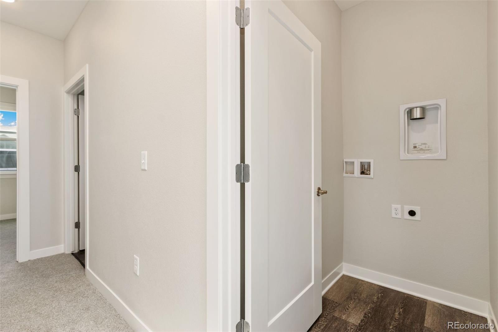 Empty laundry area with washer and dryer hookups and dark wood-look flooring.