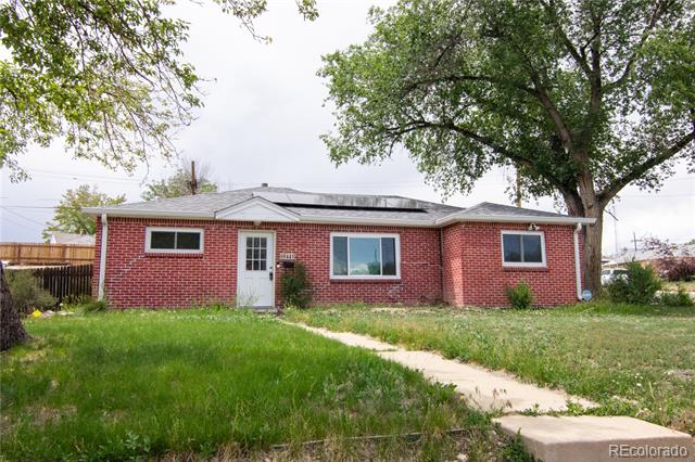Single-story red brick house with rooftop solar panels and a walkway through the front lawn.