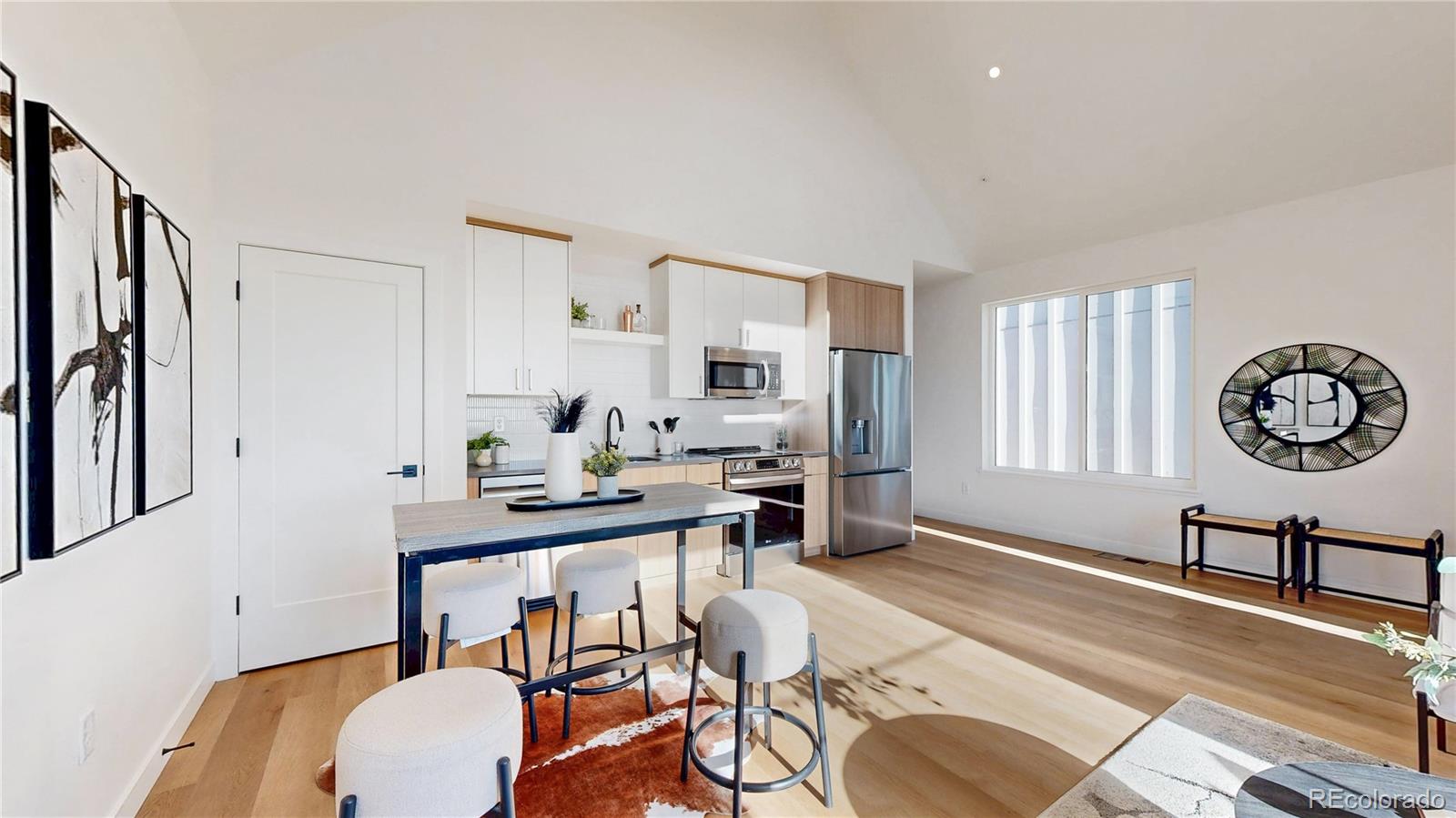 Open-plan kitchen with white cabinetry, stainless steel appliances, and a dining island.