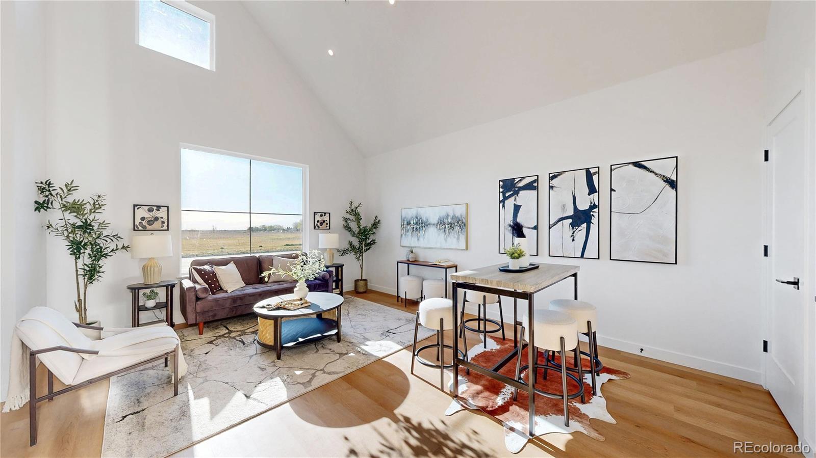 Staged living room with vaulted ceiling, large windows, and an adjoining dining area.