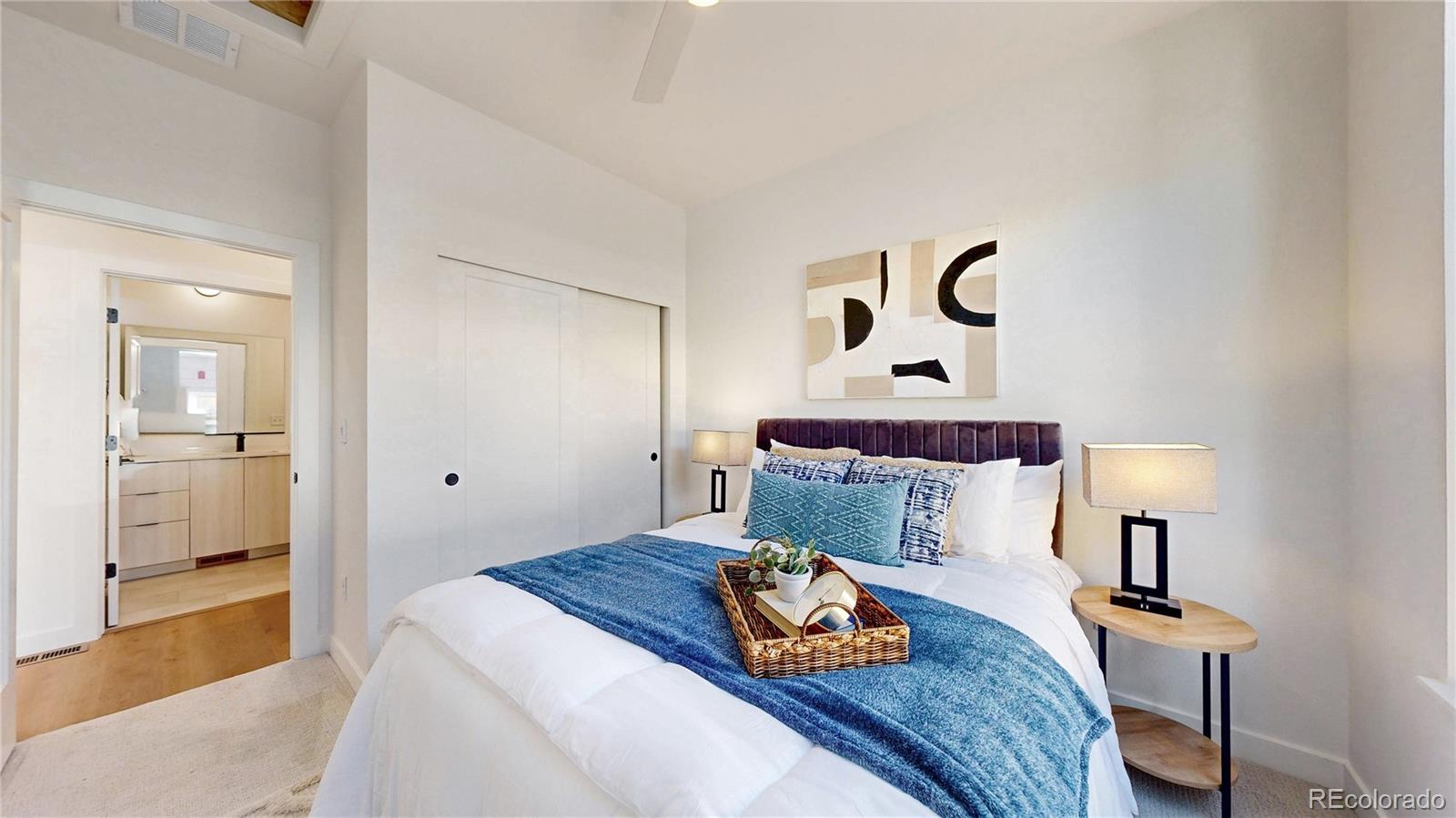 Staged bedroom with a blue throw on the bed and an adjoining bathroom vanity.