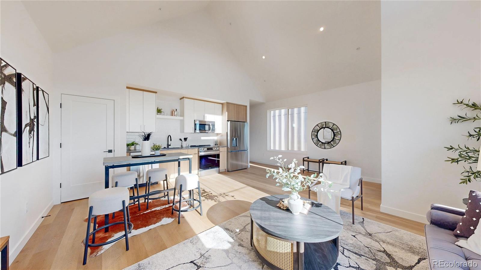 Open living and dining area with a modern kitchen, breakfast bar, and light wood floors.