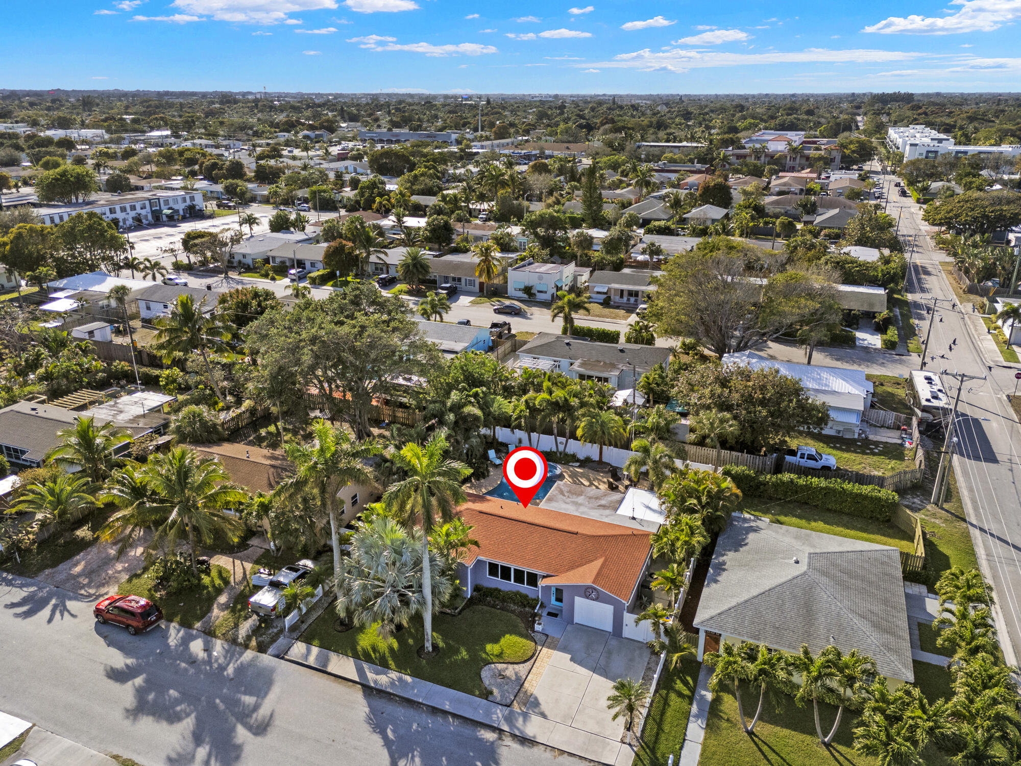 Aerial view of 1525 N L Street, a red tile-roofed home among palms and neighboring houses.
