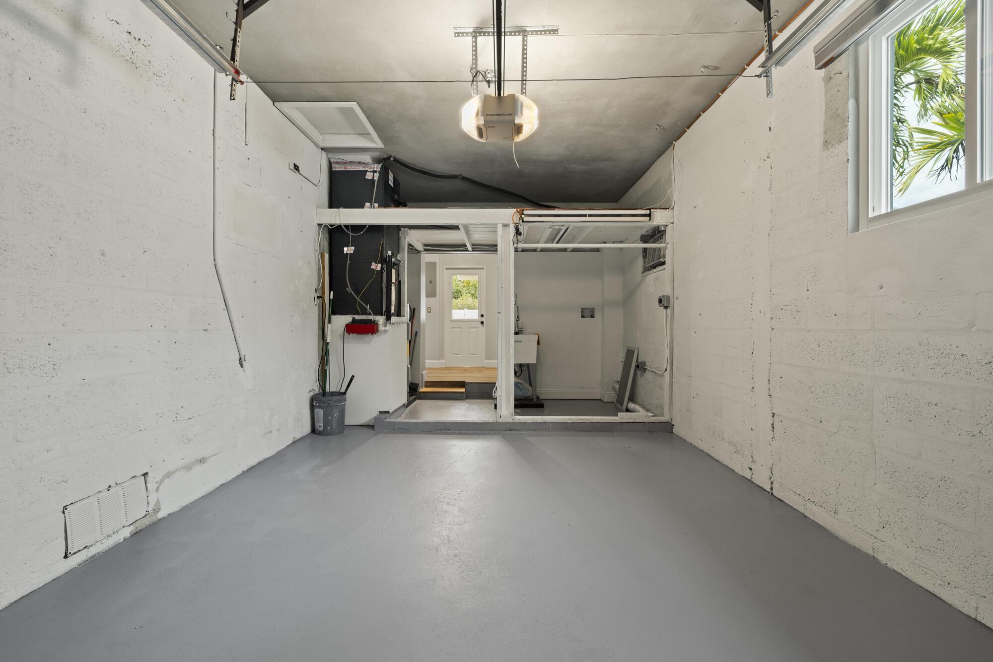 Empty garage with gray floor, concrete-block walls, and a utility area at the far end.
