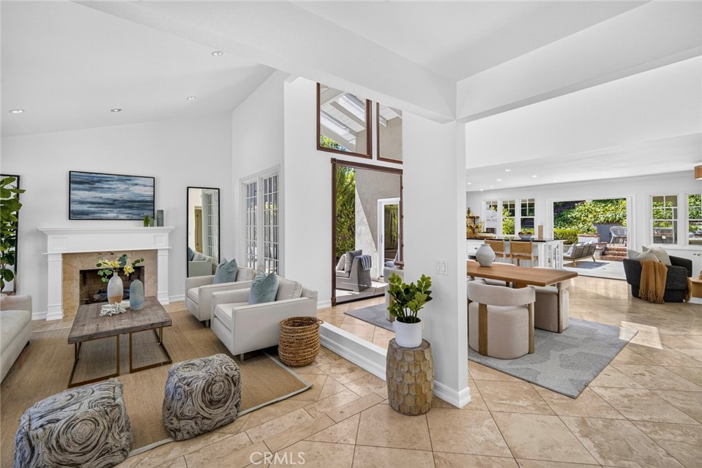Open-plan living room with a white fireplace, high ceilings, and views into the dining area and kitchen.