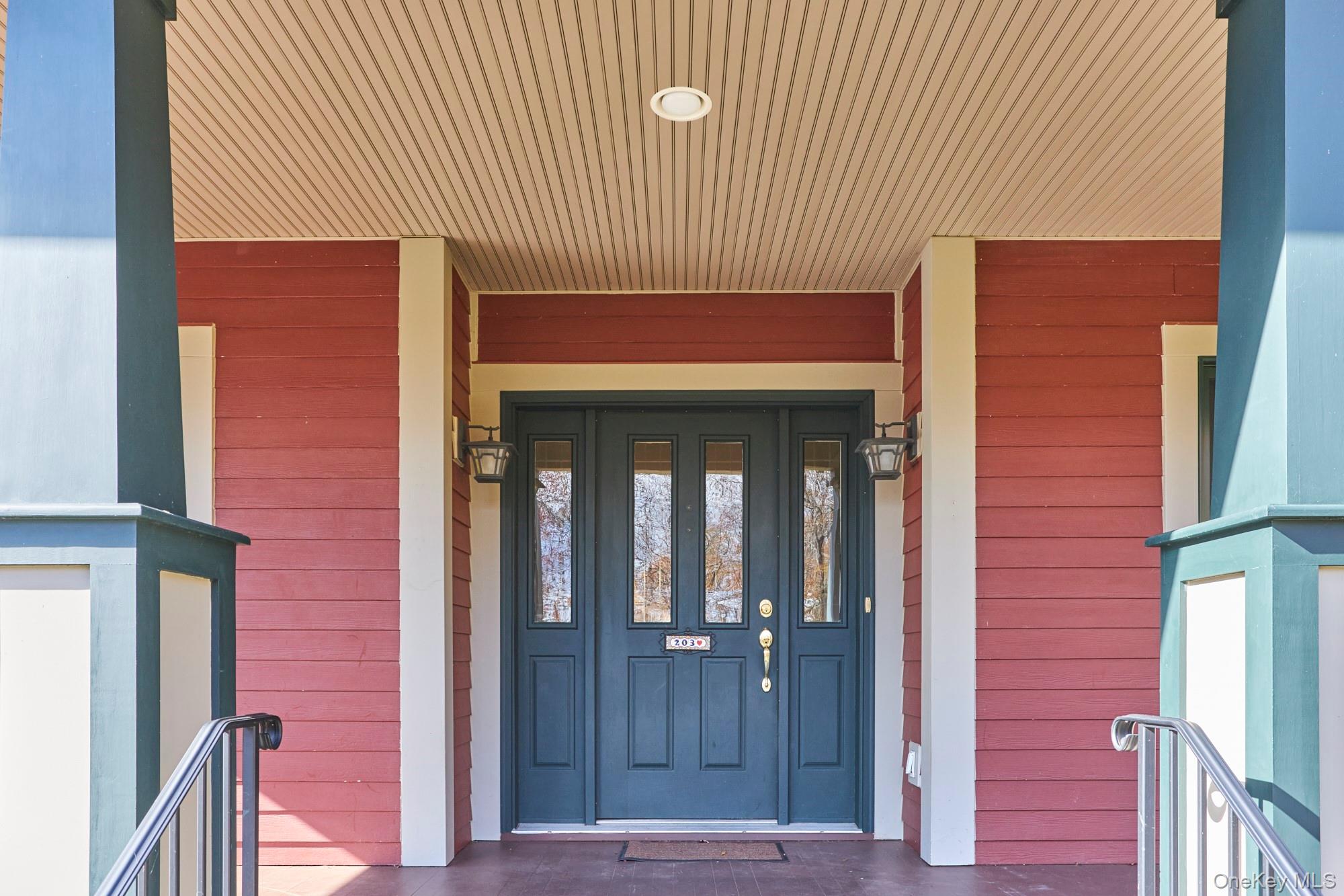 Covered front entrance with dark blue double doors, red siding, and cream trim.