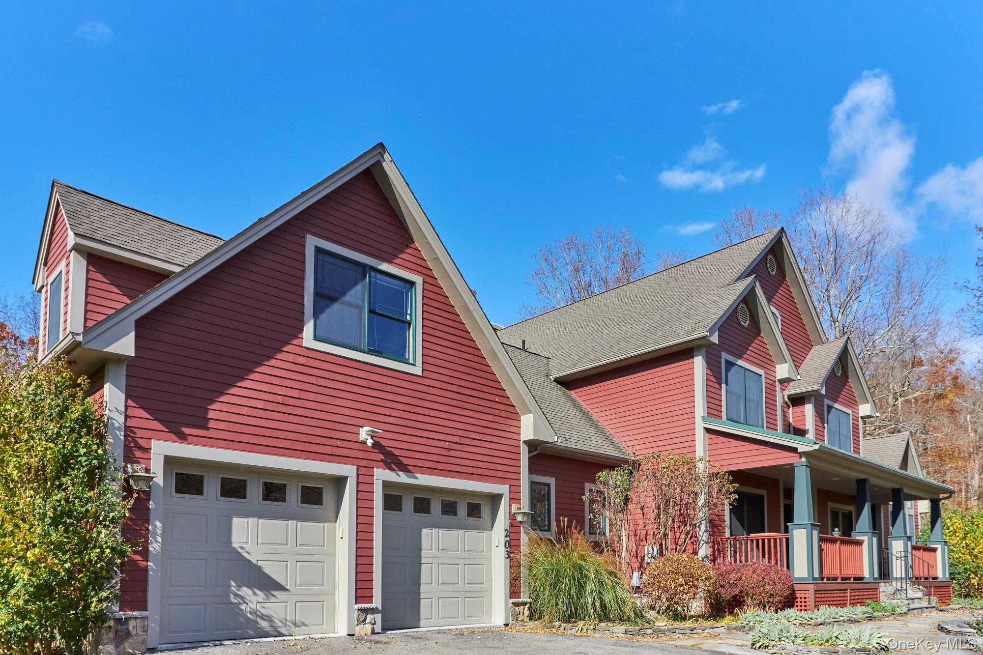 Red-sided home with multiple gables, two garage doors, and a covered porch.