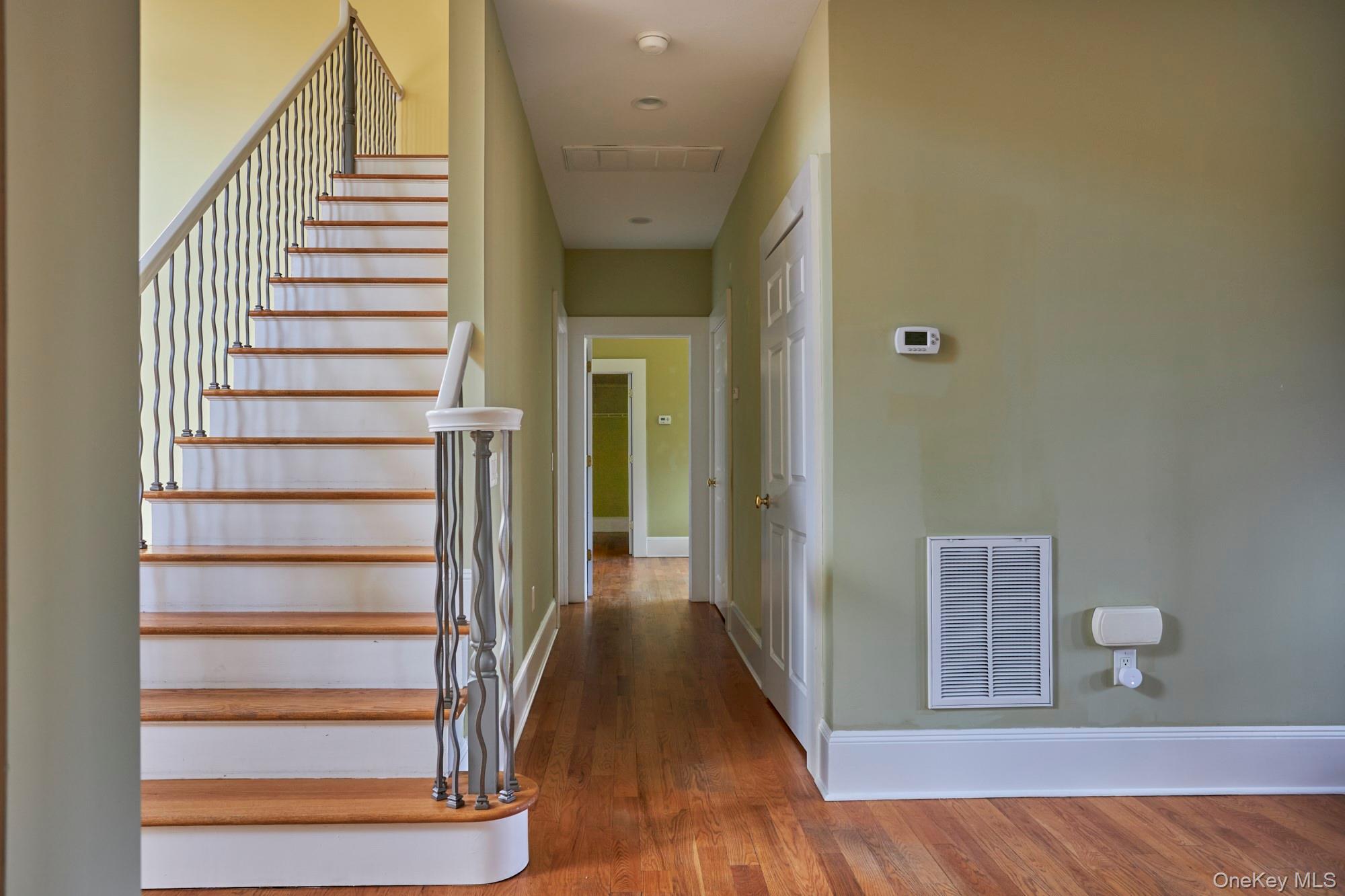 Entry hallway with a wood-tread staircase, dark metal balusters, and hardwood floors.