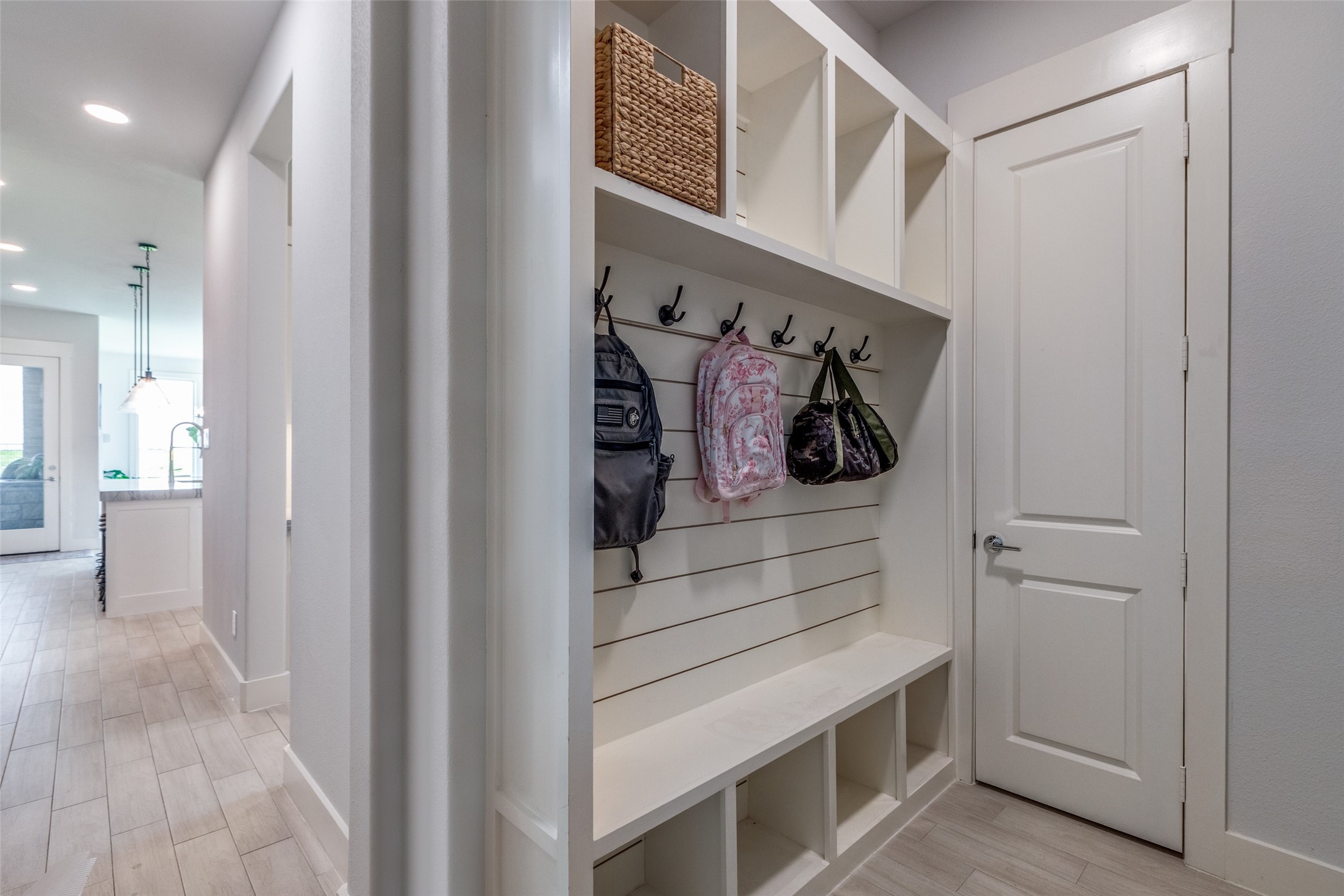 Built-in mudroom bench with overhead cubbies and backpacks hanging from wall hooks.