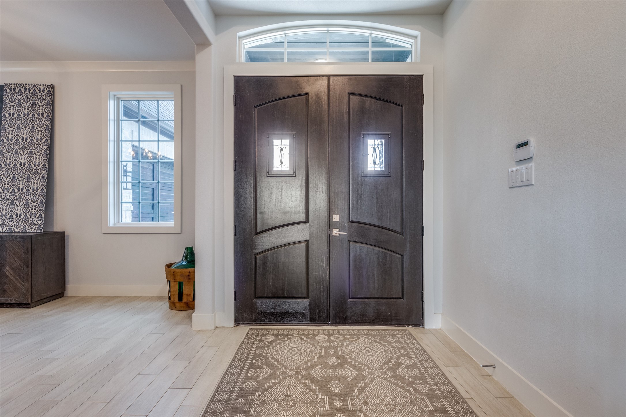 Entry foyer with dark double front doors, an arched transom window, and a patterned runner rug.