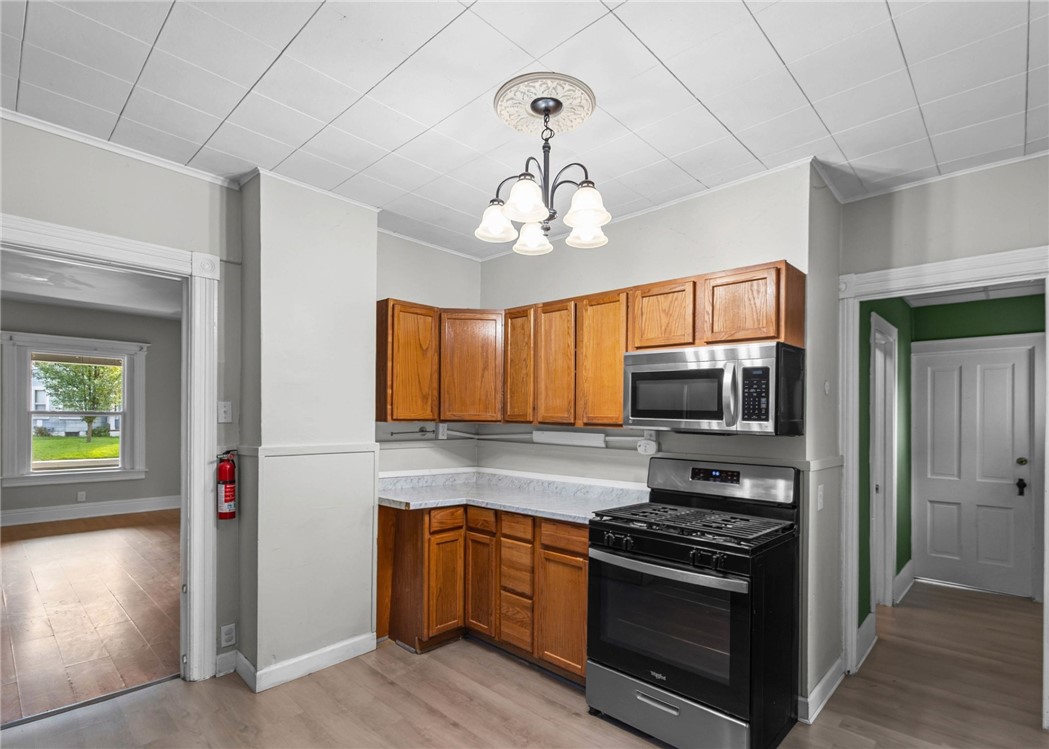 Kitchen with warm wood cabinets, light countertops, and black stainless-steel range and microwave.