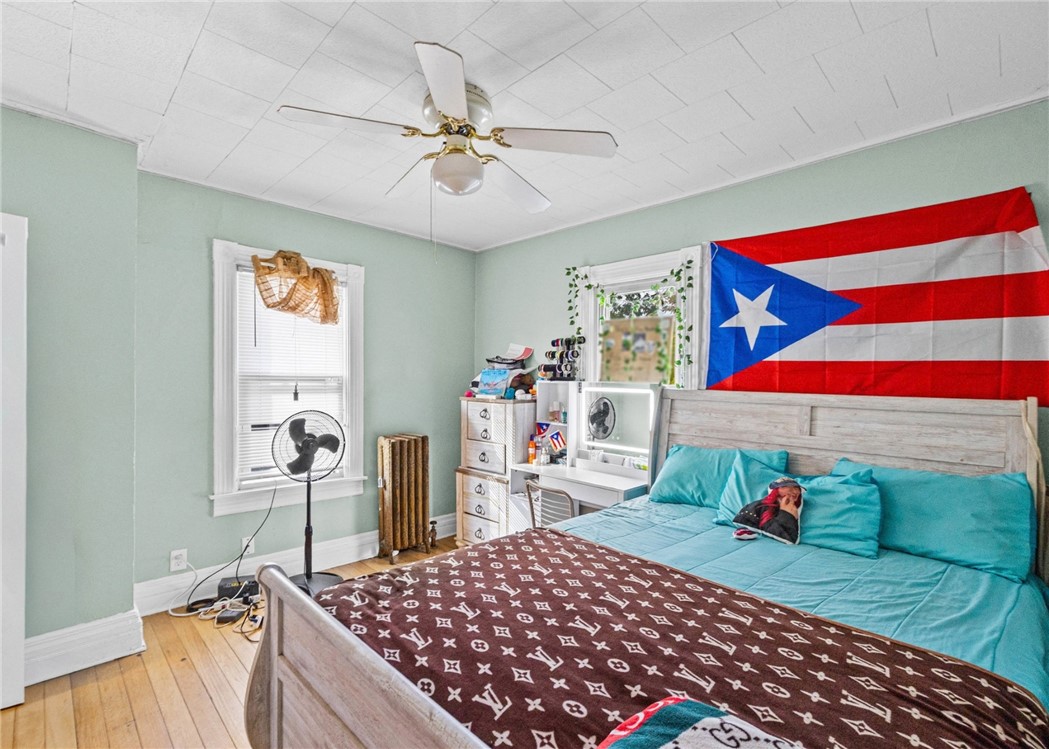Bedroom with turquoise bedding, a light wood bed, and a Puerto Rican flag above the headboard.