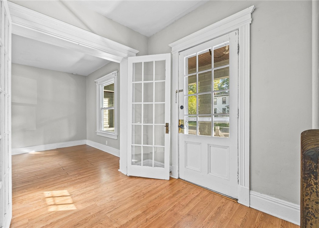 Entry room with hardwood floors and white glass-paneled doors, including an open interior door.