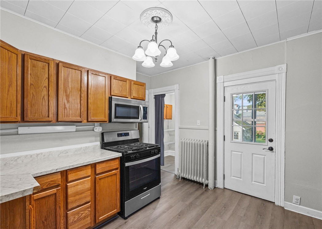 Kitchen with wood cabinets, marble-look counters, black appliances, and a glass-panel door.